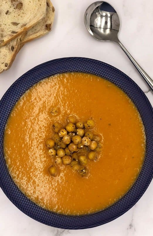 Tasty bowl of butternut squash, leek and carrot soup with a fried chickpea topping