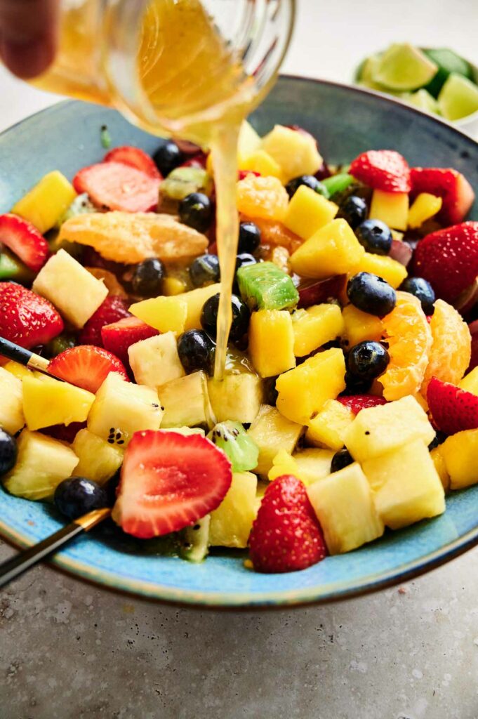 A delectable fruit salad being drizzled with refreshing lemon juice.