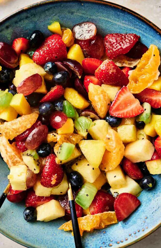 A refreshing fruit salad served in a vibrant blue bowl.
