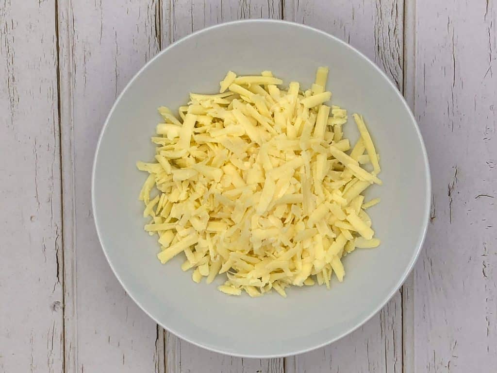 Grated cheddar cheese in a white bowl
