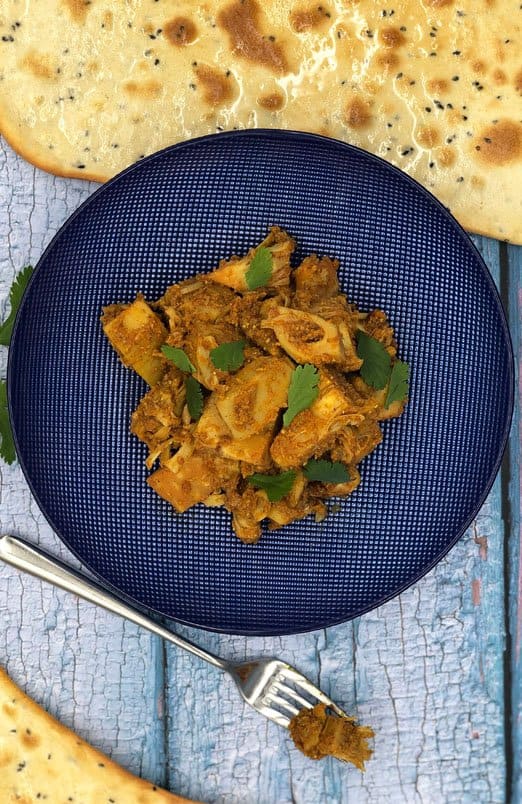 Jackfruit curry with naan bread on a blue plate