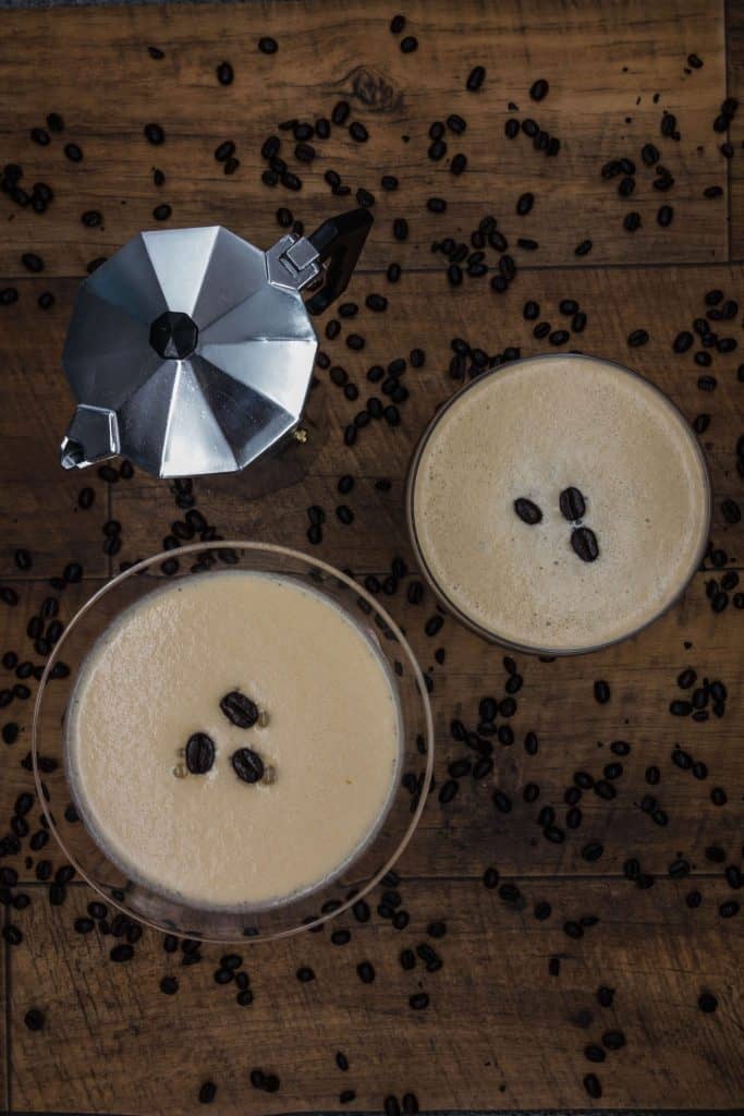 Overhead shot of two espresso martinis and an espresso stove top pot with freshly brewed coffee ready for serving