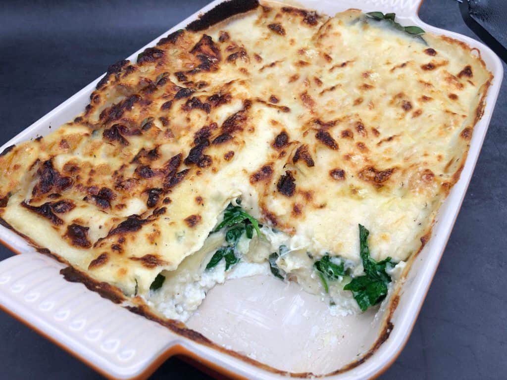 An oven dish with a four cheese lasagne with a slice removed