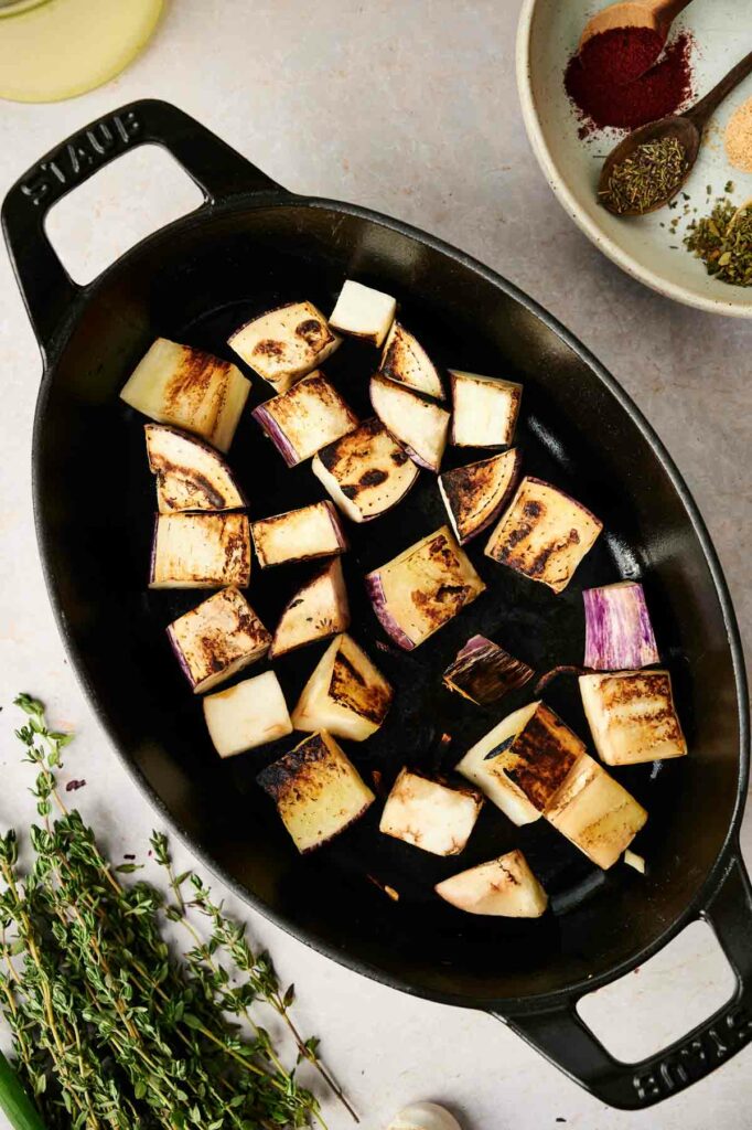 Ratatouille recipe featuring grilled eggplant in a cast iron pan with herbs and spices.