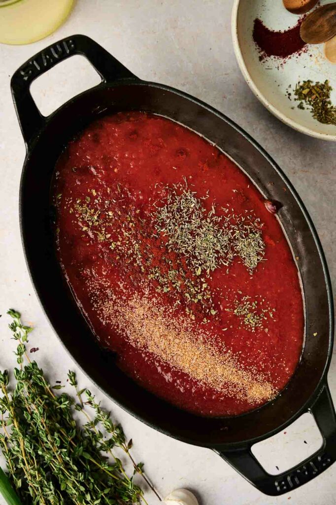 A ratatouille recipe prepared in a cast iron pan with tomato sauce and herbs.