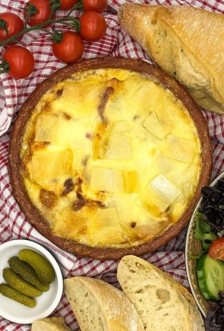 A dish of cheesy tartiflette savoyarde with French bread and salad