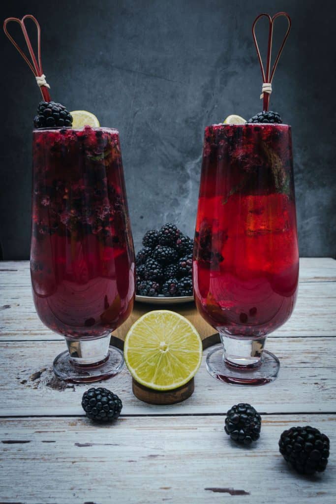 Tasty blackberry mojito with a plate of  blackberries and half a citrus fruit
