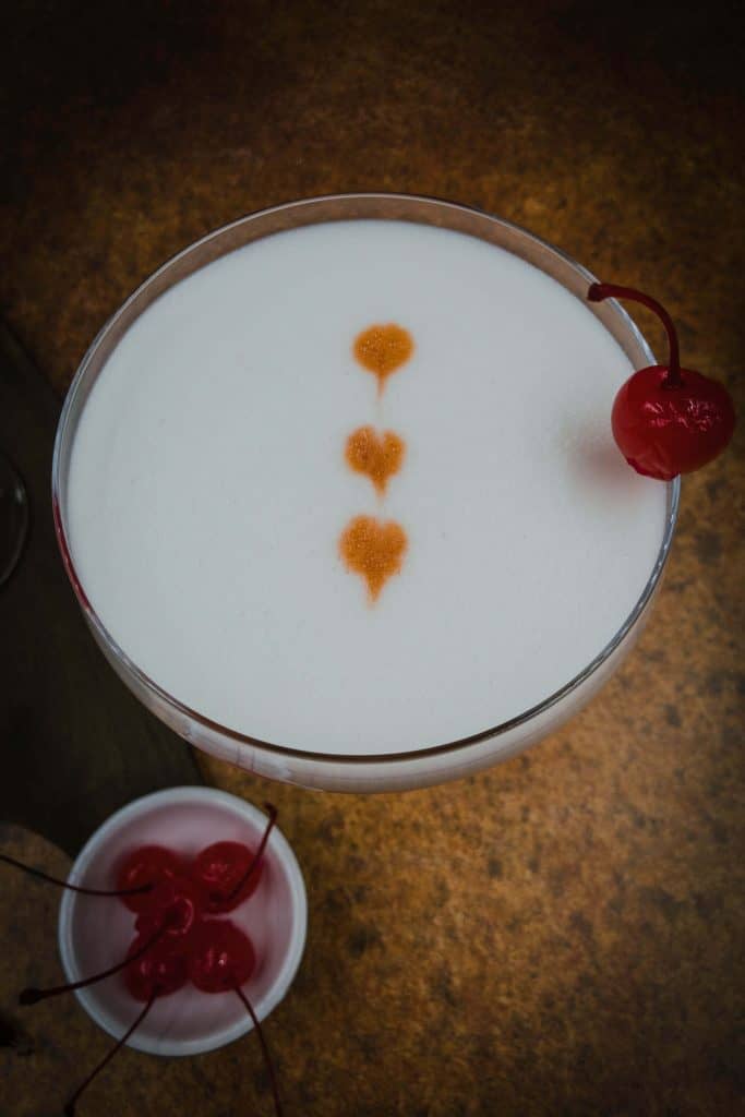 Frothy top on a whiskey sour made with egg white, Maraschino cherry garnish with Angostura bitters