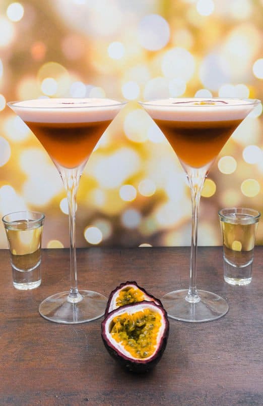 Two stunning alcohol free pornstar martini cocktail drinks with fresh passion fruit and a shot of alcohol free champagne