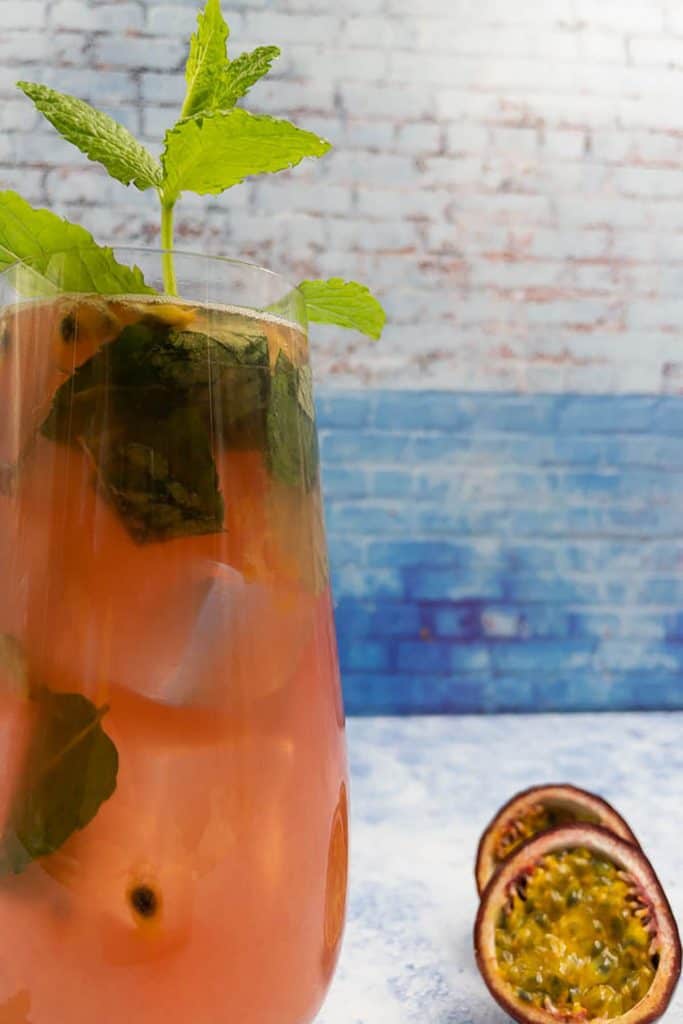 Close up of passion fruit mojito with fresh passion fruit and sprig of mint leaves