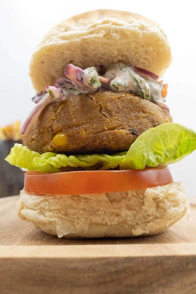 Chickpea veggie burger in a bun, with lettuce, tomato and red cabbage slaw