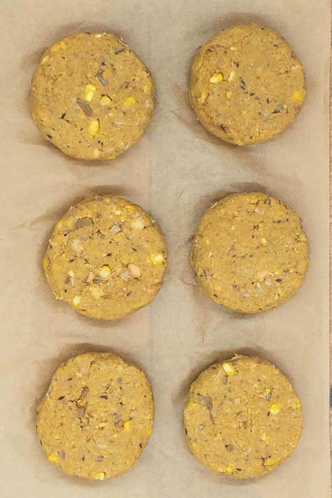 Six chickpea patties shaped and resting on parchment paper