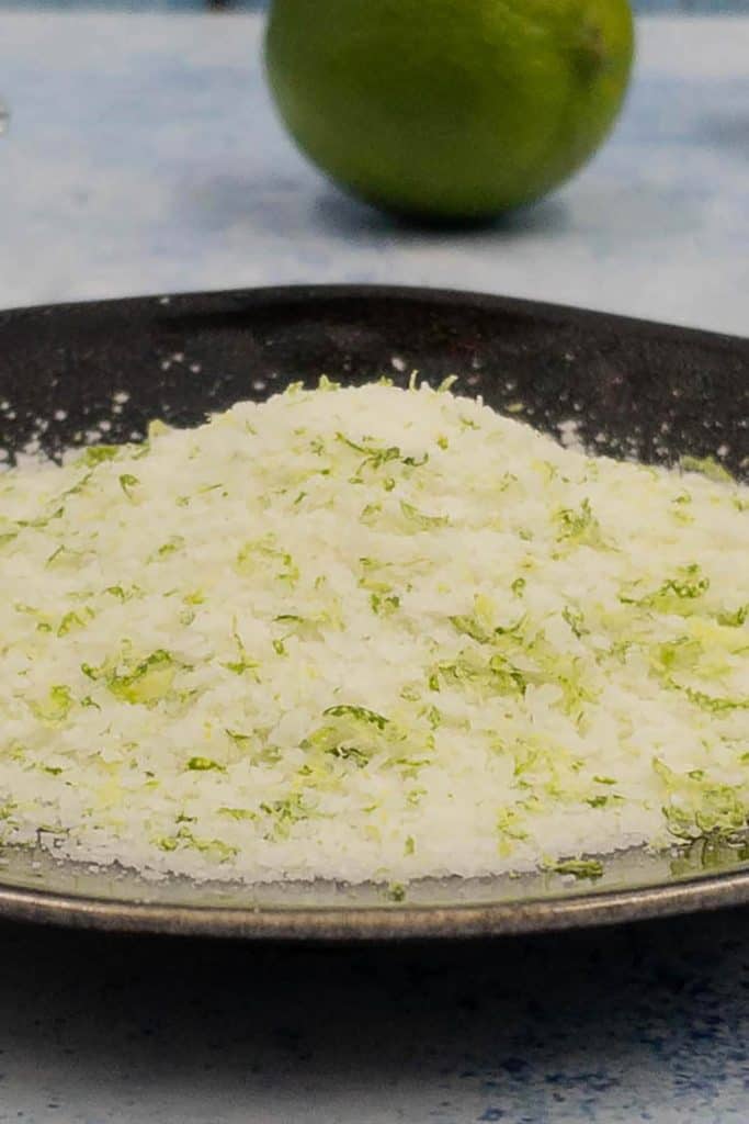 Plate of lime zest with flaky salt ready to rim the glass of a watermelon margarita.