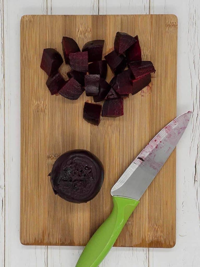 Roasted beets, some cut into wedges on a chopping board