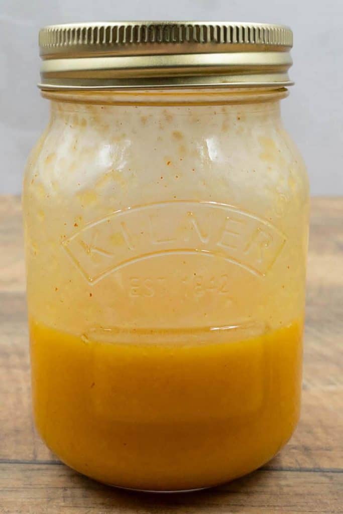 Fresh homemade chili and lime salad dressing in a mason jar just after a good shake.