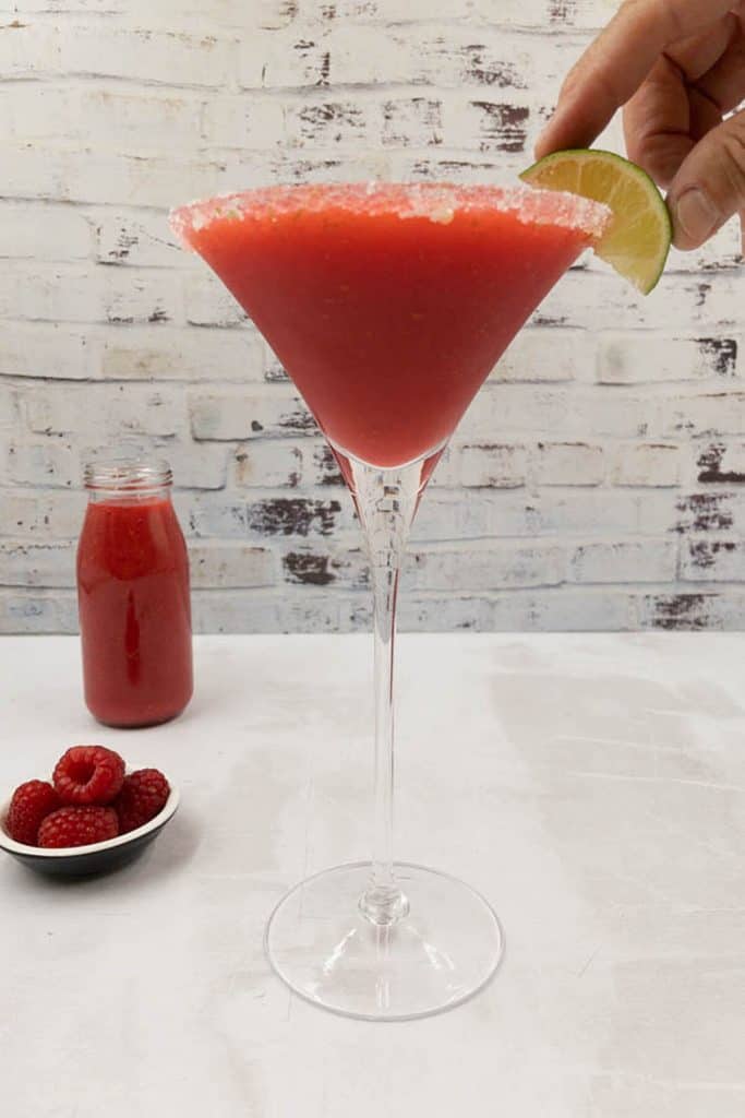 Placing the lime wedge garnish on a delicious fruity raspberry daiquiri.