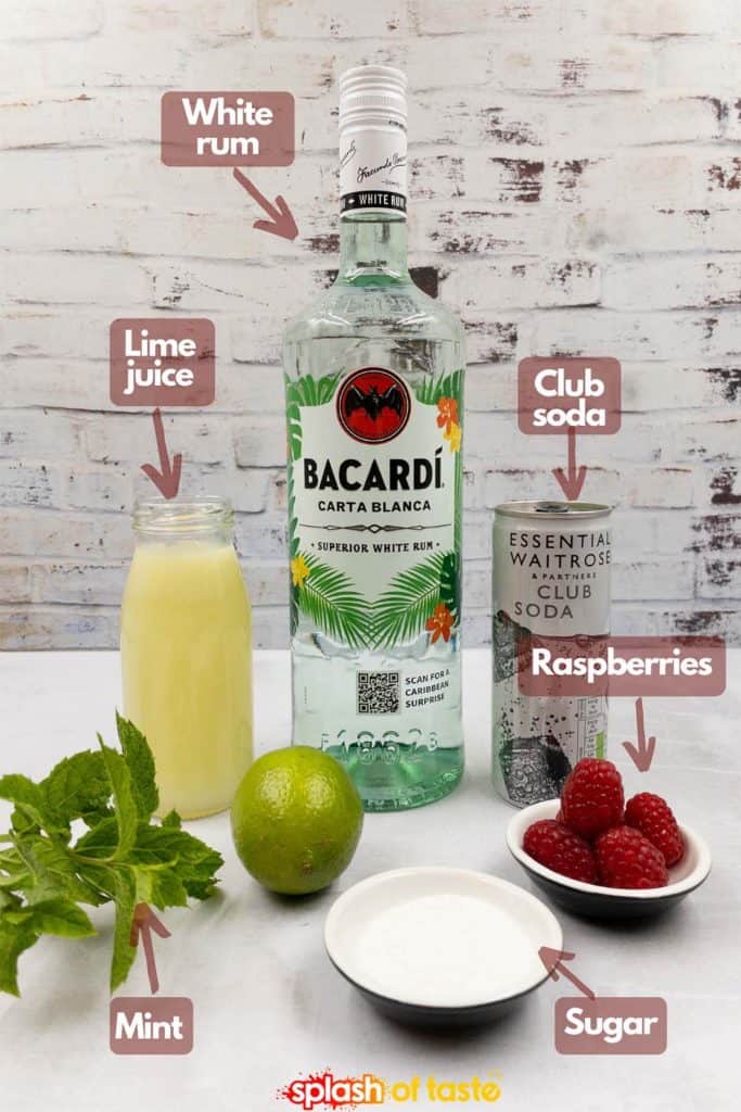Ingredients to make a raspberry mojito cocktail, lime juice, white rum, club soda water, fresh raspberries, sugar and fresh mint.