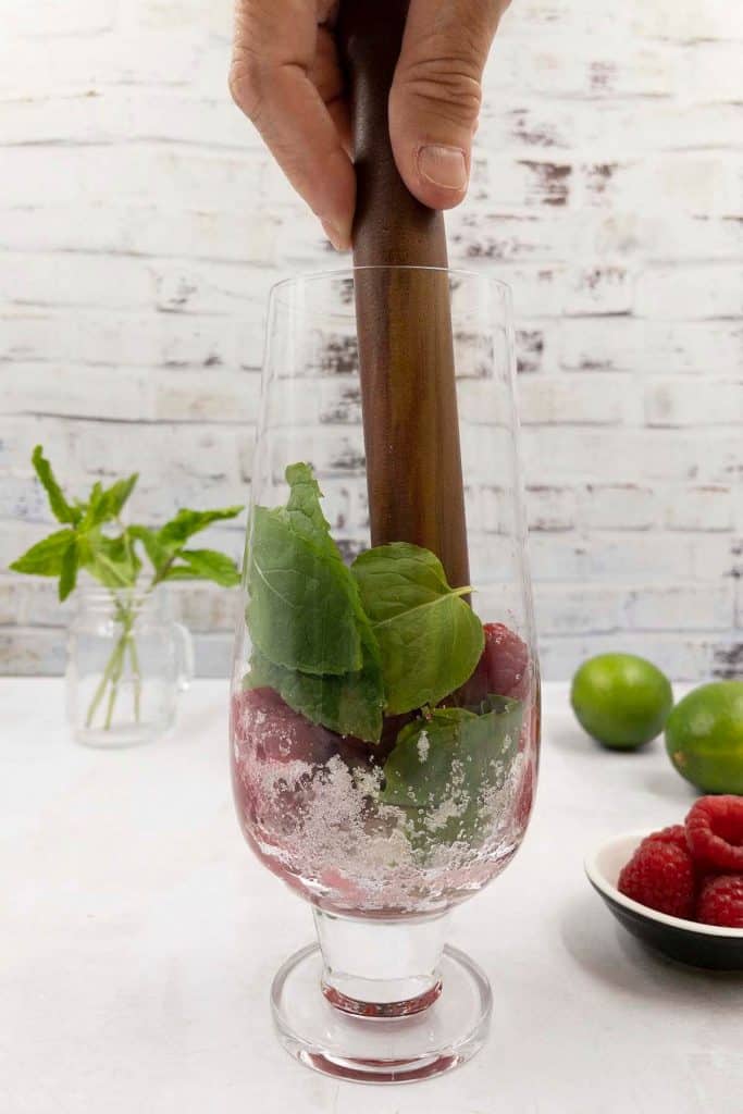How to muddle raspberries, mint and sugar for raspberry mojitos.