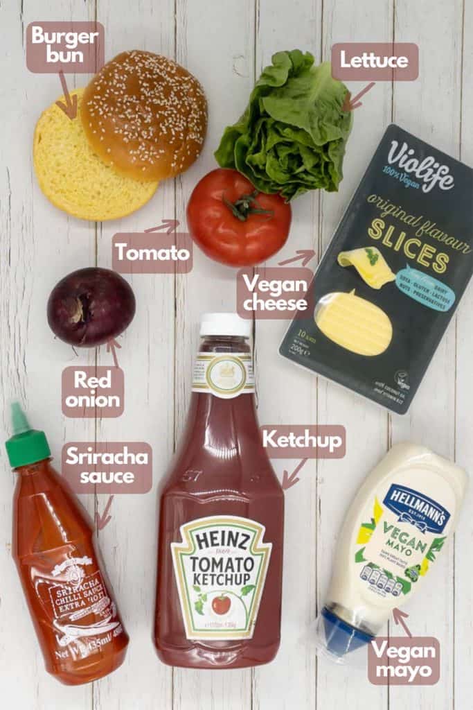 Ingredients to make vegan seitan burger sauce, burger bun, lettuce, tomato, vegan cheese, red onion, ketchup, vegan mayo and sriracha sauce