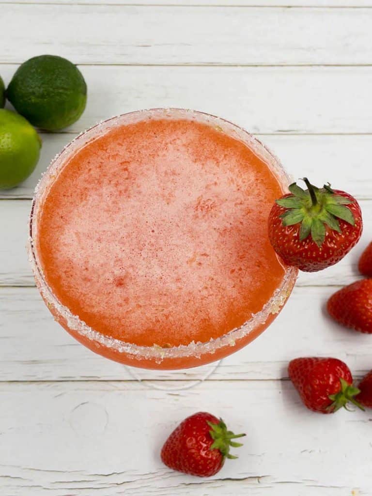 A stunning strawberry daiquiri drink in a coupe glass, with a strawberry garnish.