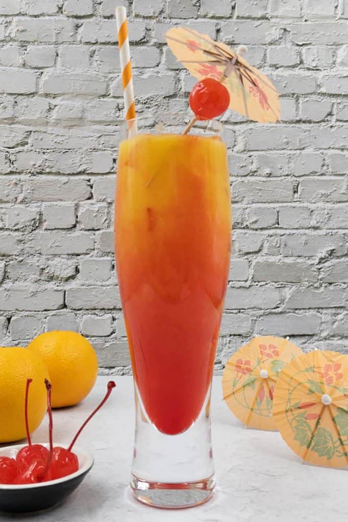 Stunning vodka sunrise cocktail in a glass with cherries, umbrellas and ready to drink.