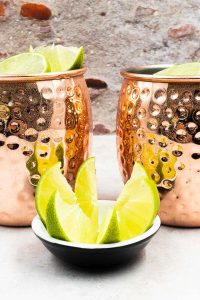 Two spicy Mexican mule cocktails, the mules have ice and wedges of lime.
