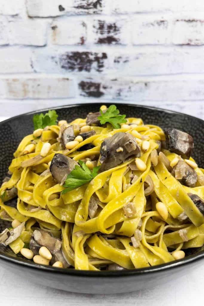 A tasty bowl of mushroom pasta ready to eat, with mushrooms, fresh herbs and pine nuts.