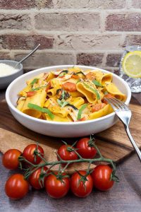 A delicious meal of homemade pasta alla sorrentina, with paccheri pasta tubes, cherry tomatoes, with chopped basil on top.