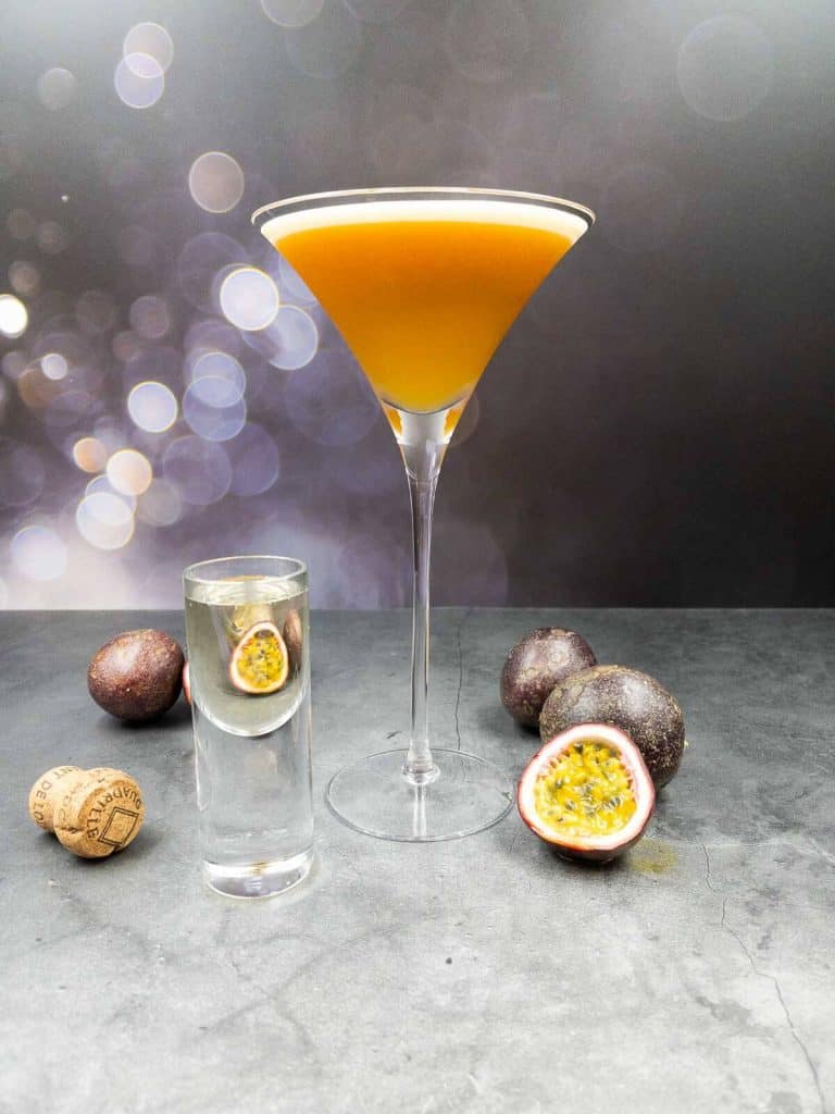 Delicious fruity pornstar martini gin cocktail with fresh passionfruit around it.