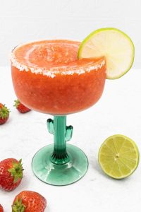A ice strawberry margarita made from scratch with a lime wheel garnish.