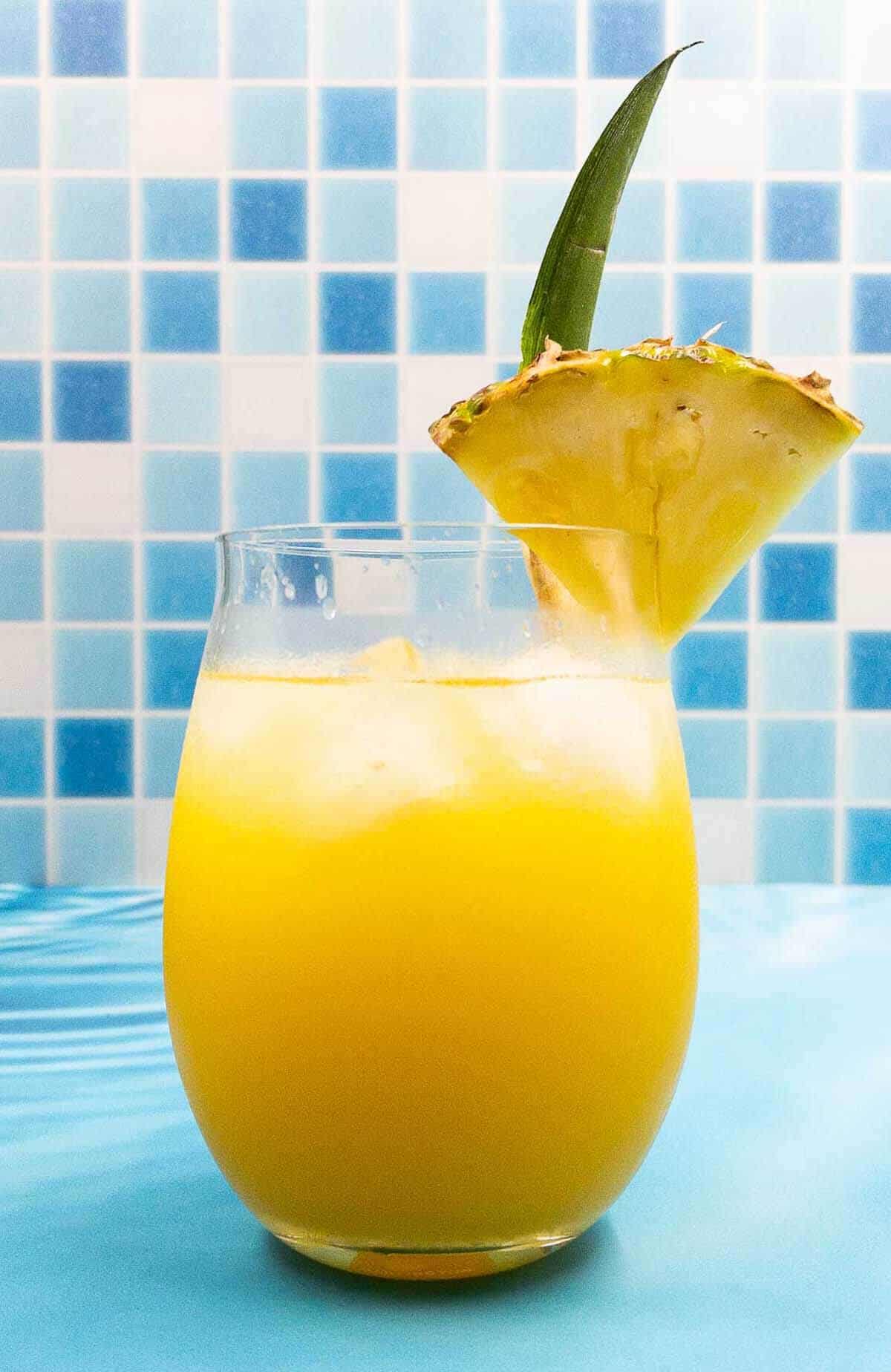 A homemade pineapple tequila cocktail with a wedge of pineapple garnish.