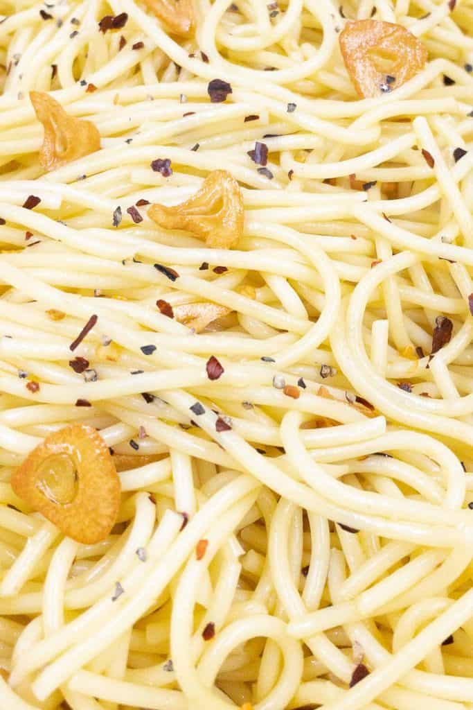 Close up of spaghetti aglio e olio, thin garlic slices, olive oil and red pepper flakes.