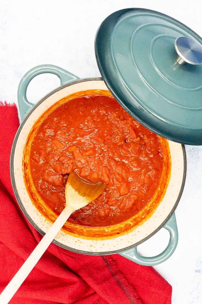A pot of arrabbiata sauce cooking with a wooden spoon.