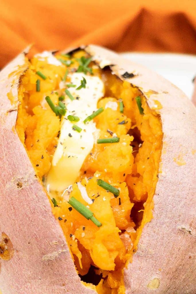 Delicious baked sweet potato fresh out of the oven, with a pat of butter, chives and kosher salt.