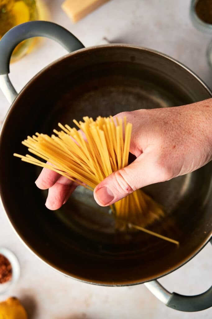 A person pouring pasta into a pot.