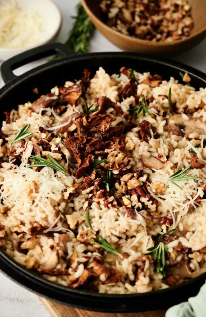 Homemade mushroom risotto in a pot with rosemary and grated cheese.