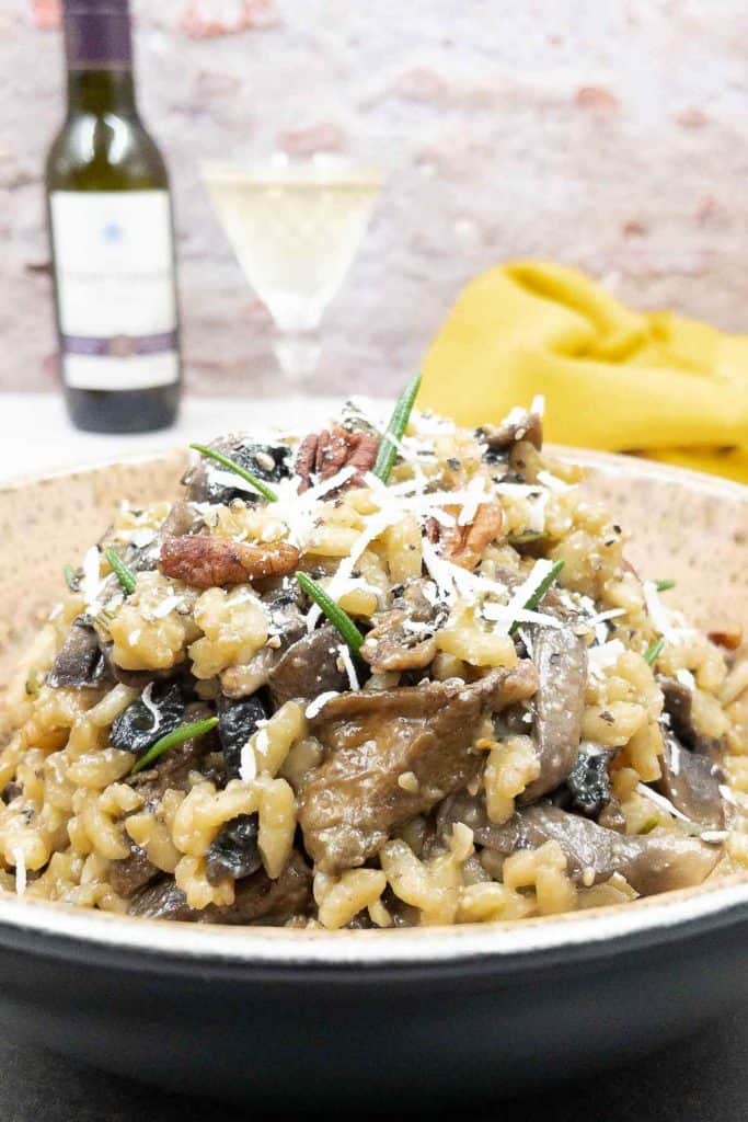 Homemade mushroom risotto in a bowl with rosemary and grated cheese.