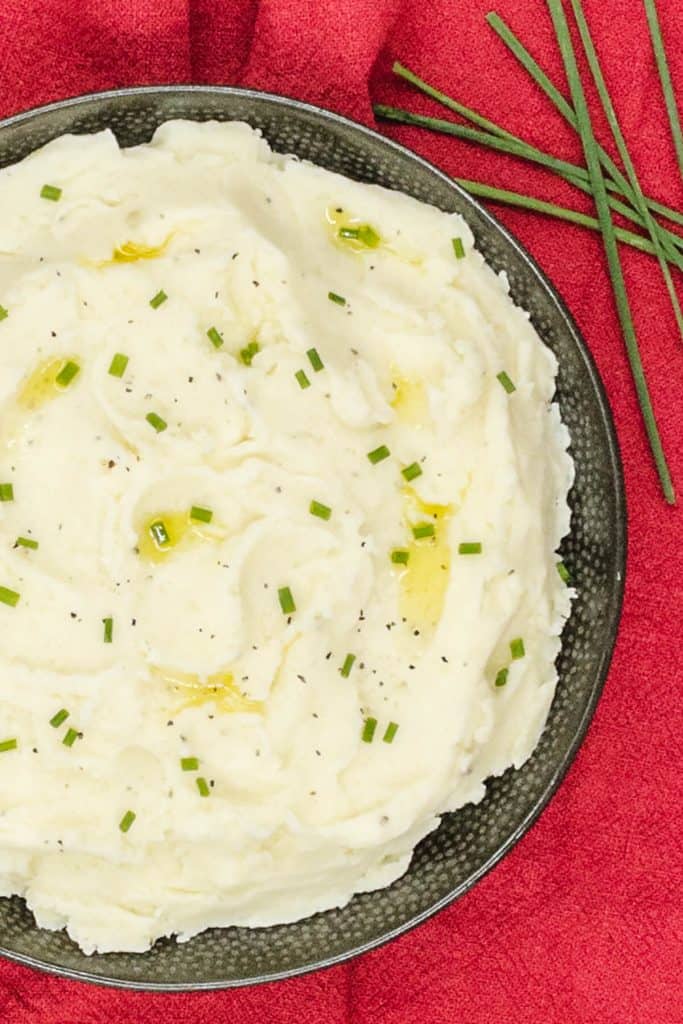 Close up of homemade mashed potato with fresh chives and melted butter.