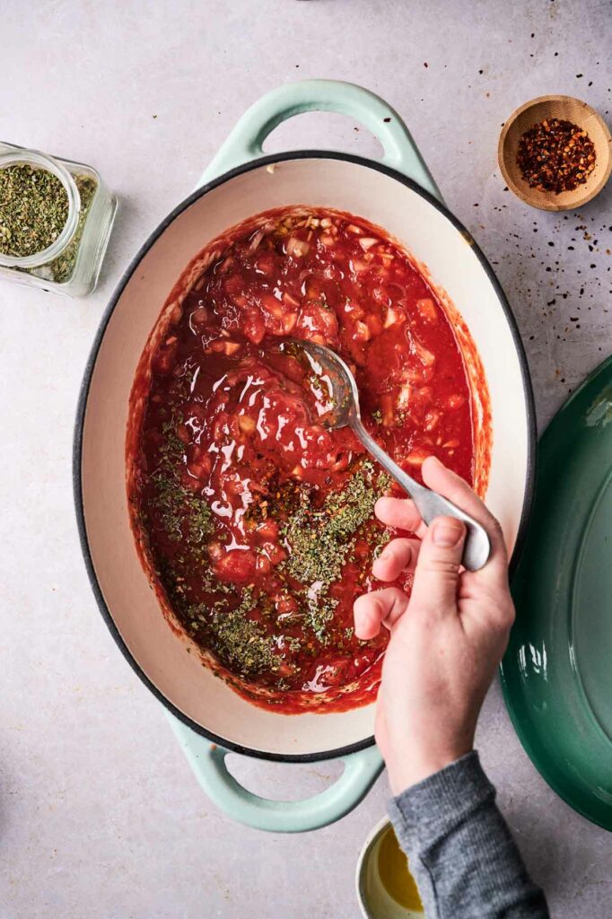 A person pouring tomato sauce into a pot to make spaghetti marinara.