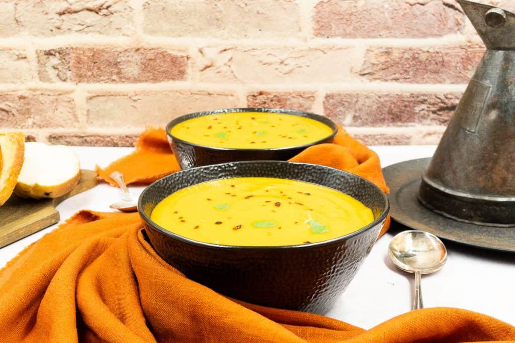 Two bowls of homemade creamy sweet potato soup ready to eat.
