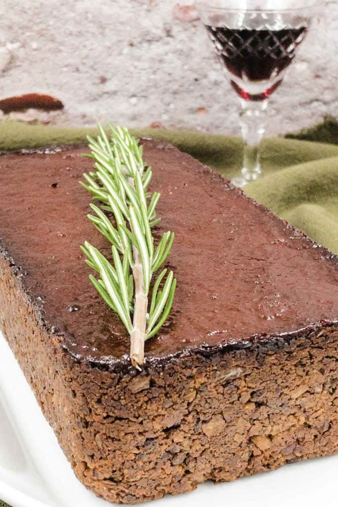A lentil loaf, freshly made with a sprig of rosemary on top.
