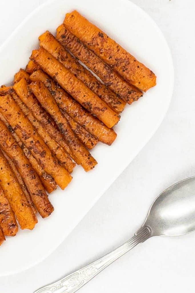 A plate of roasting carrots made from scratch with a spoon.