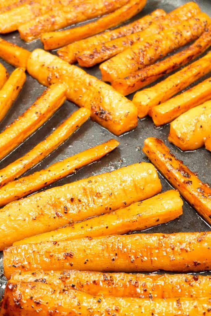 Close up of roasting carrots in the oven, caramelizing while cooking.