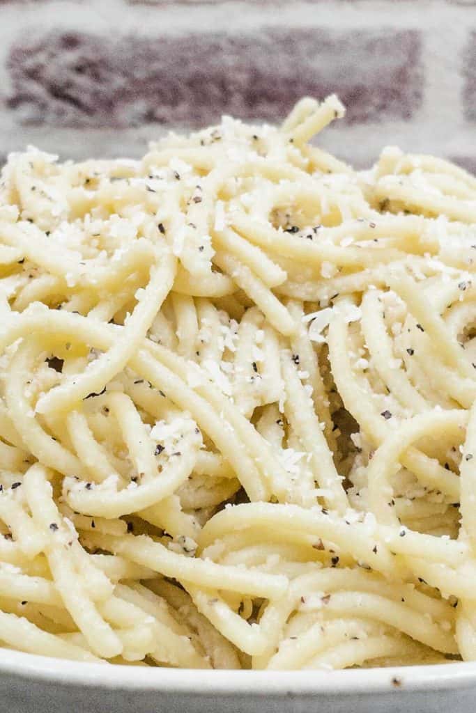 Close up of cacio e pepe spaghetti with grated cheese to garnish.