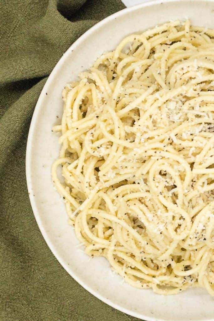 Cheese and ground black pepper sauce on spaghetti in a bowl.