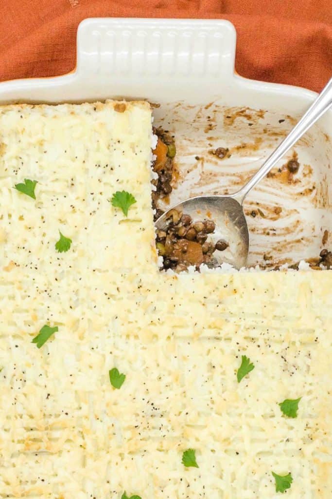 Close up of a vegetarian pie with a portion removed and lentils on the spoon.