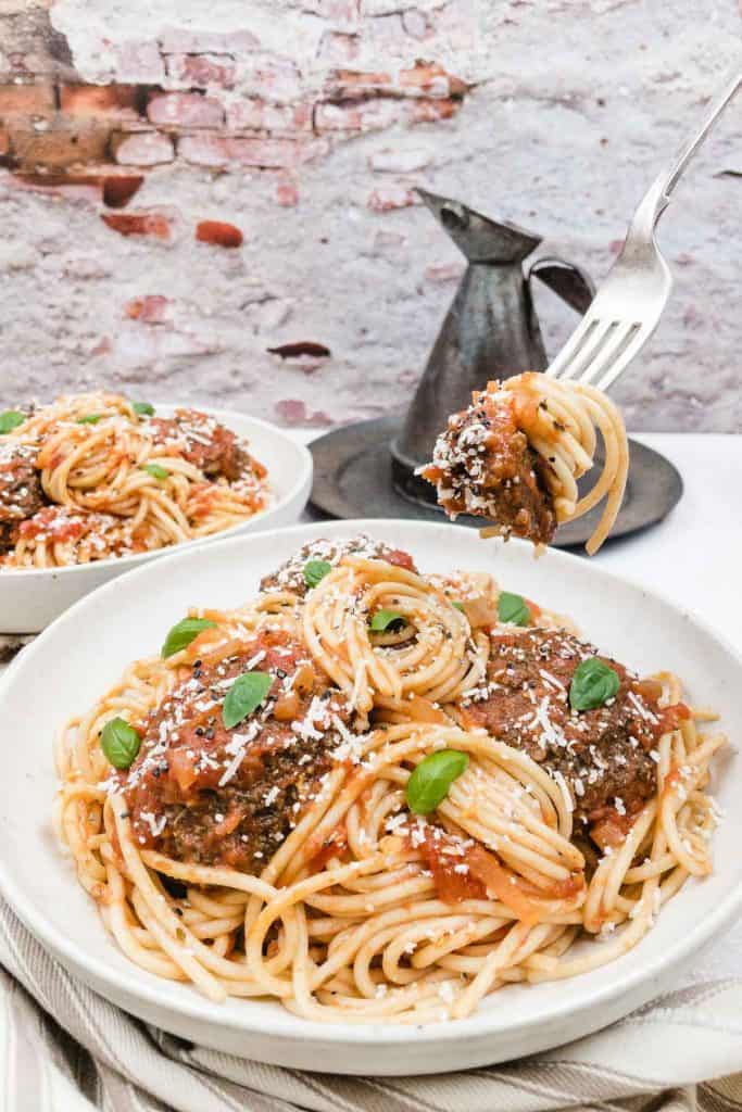 Vegetarian spaghetti and meatballs in a bowl with a fork full.