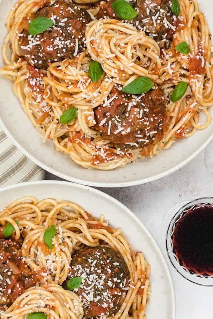 Overhead shot of vegetarian meatballs and spaghetti, with a glass of red wine.