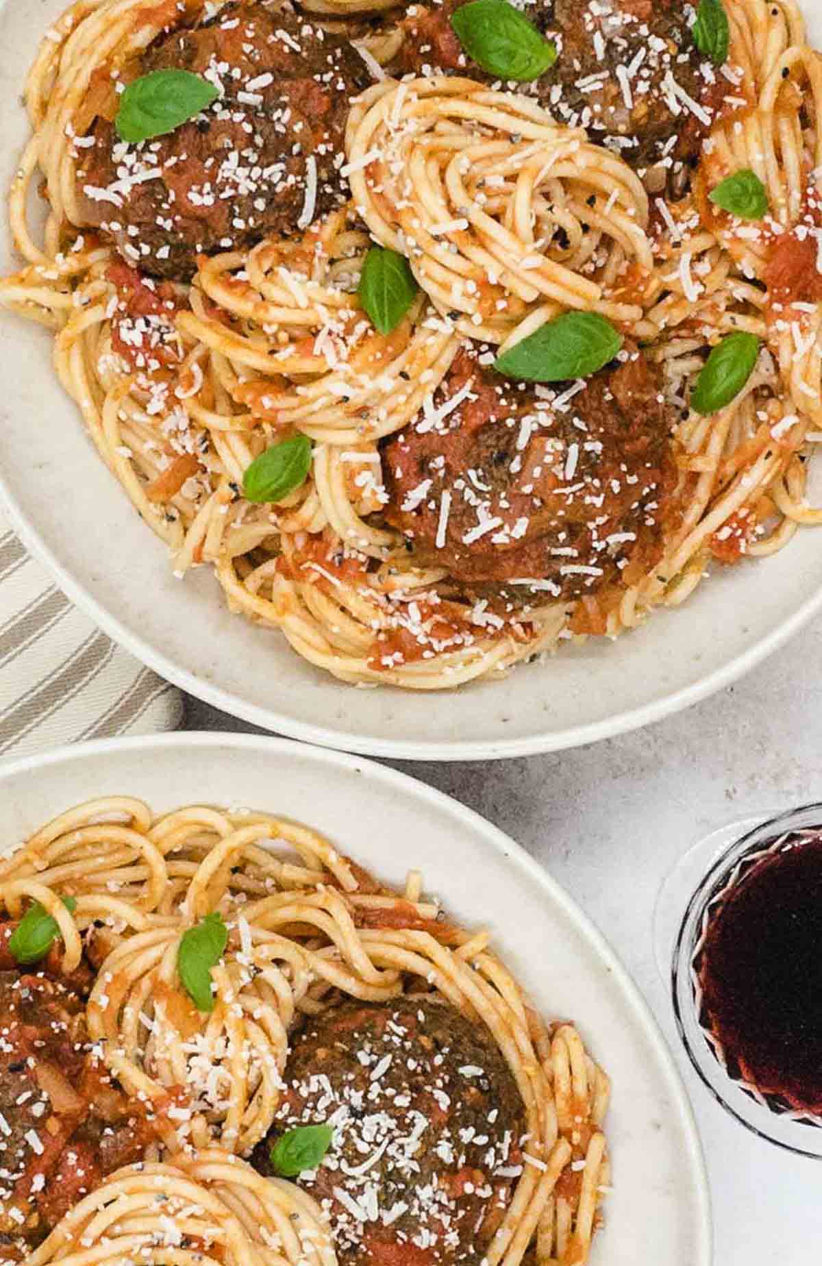 Vegetarian spaghetti and meatballs, freshly made in two bowls with fresh basil and Parmesan cheese to garnish.