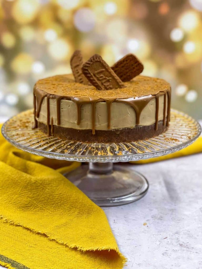 A Biscoff cheesecake on a cake stand, ready to eat.